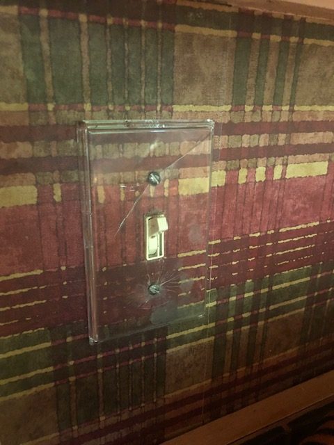 Warm colored plaid wallpaper with translucent light switch plate. 